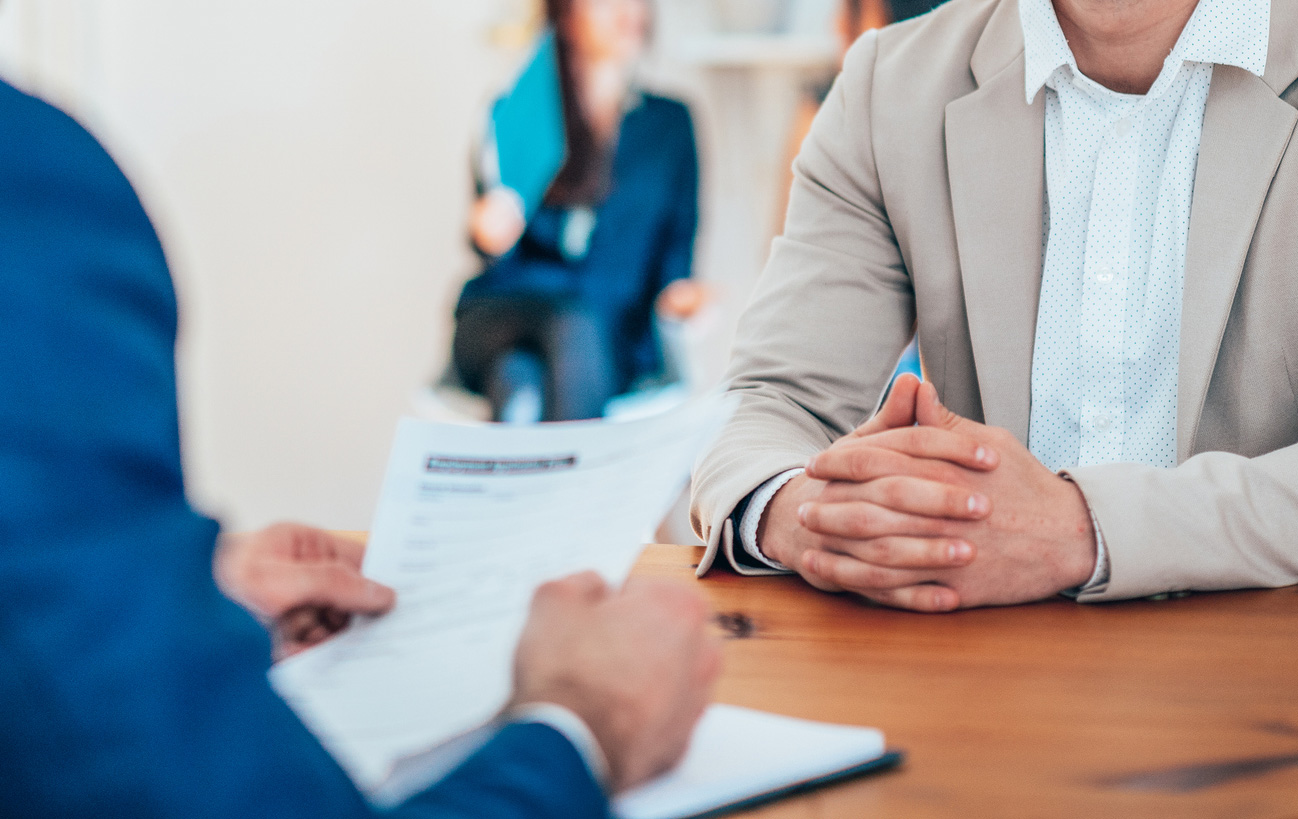 A candidate during a job interview with a senior manager holding documents